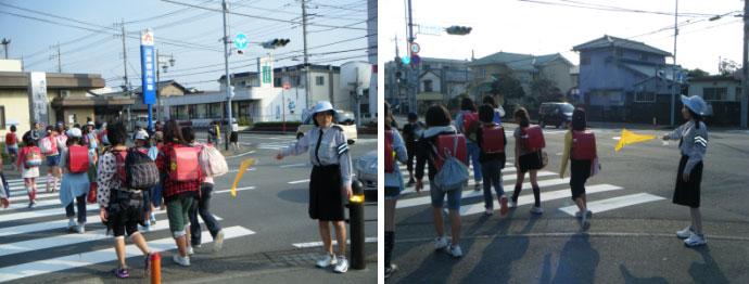 交通指導員が黄色い旗を持ち、横断歩道を渡り登校する小学生を安全に見守っている写真