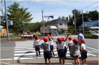 小学生が横断歩道でしっかり手を上げ渡ろうとしている写真